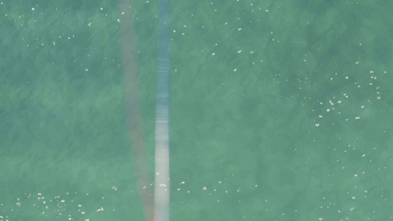 Overhead view of clear turquoise water in Baja California Sur, Mexico, with scattered white surface flecks and no visible people.