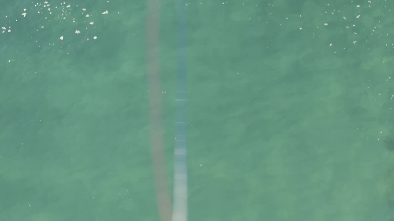 Pale turquoise water fills the overhead frame in Baja California Sur, Mexico, with scattered bright highlights and no visible people.