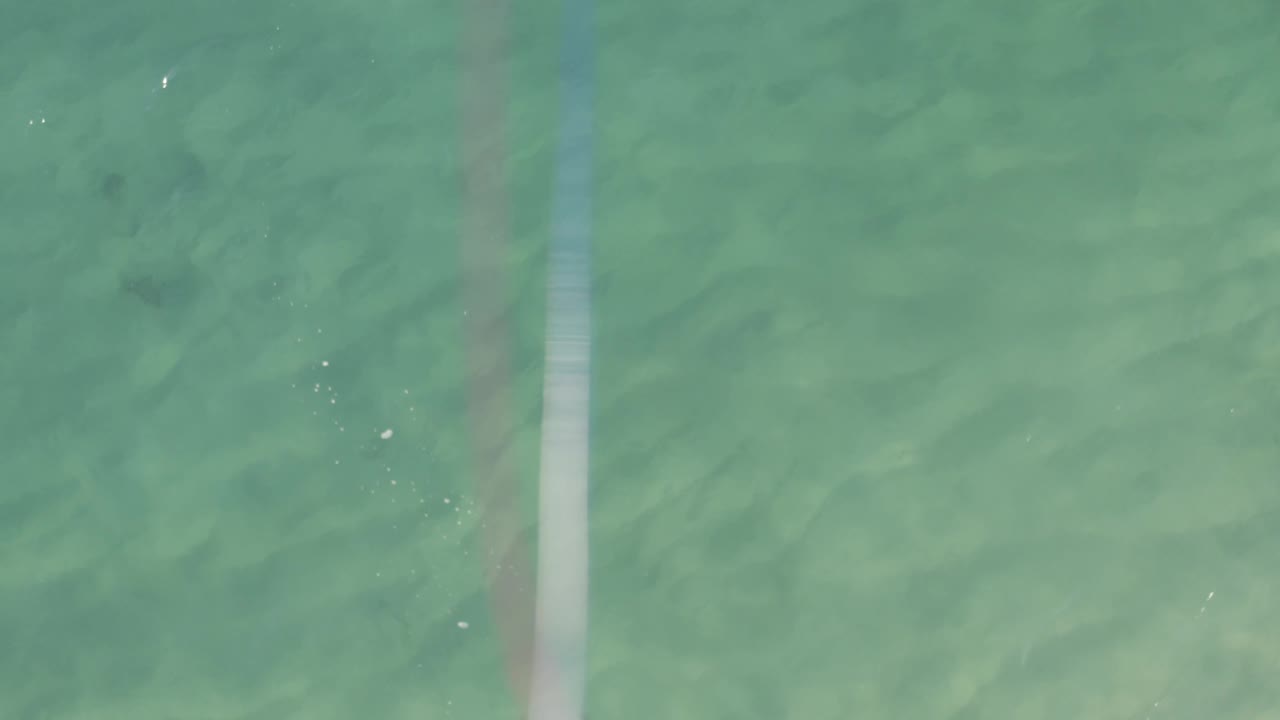 Overhead view of shallow water with a faint bright vertical band.