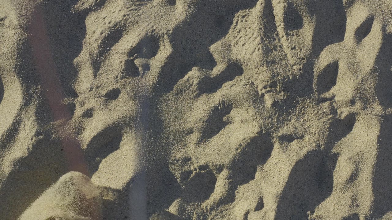 Sand close-up with a faint edge of clothing near the side.