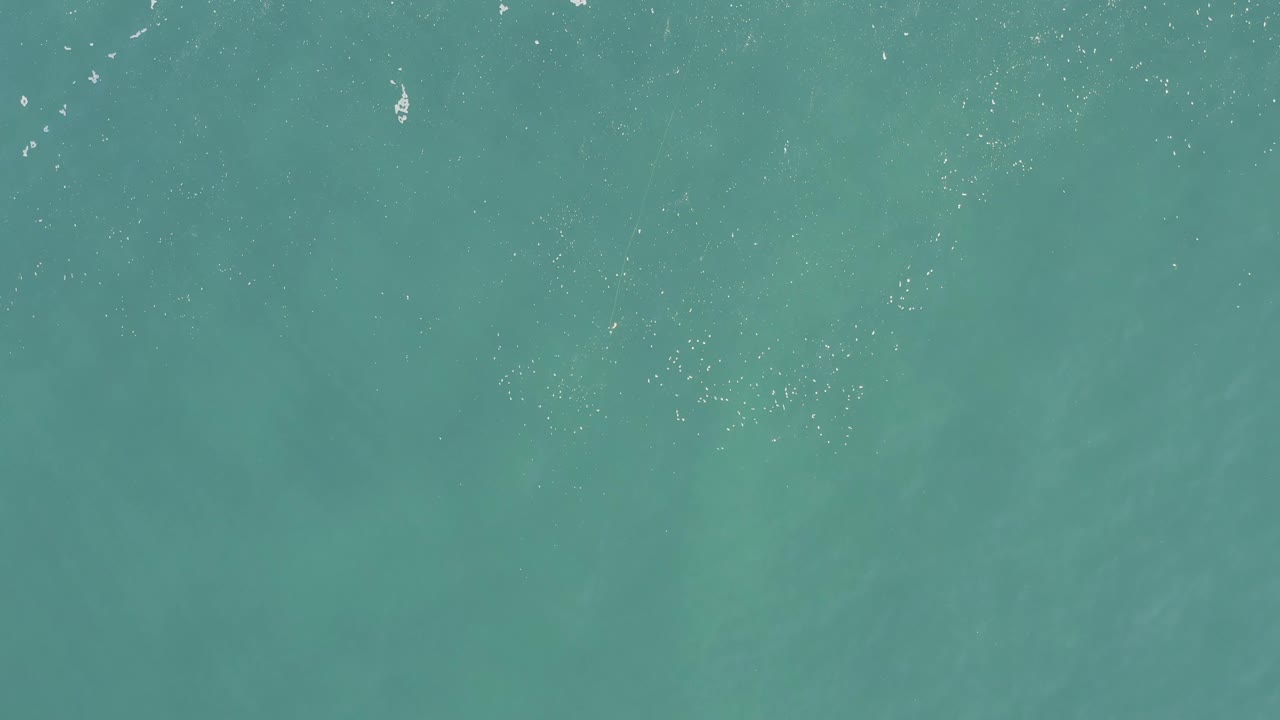 Turquoise sea surface with thin lines of white foam.