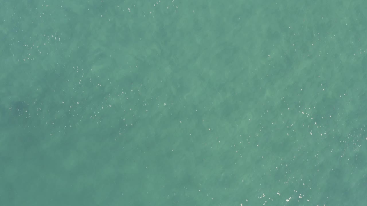 Flat overhead view of pale green-blue sea in Baja California Sur, Mexico, with sparse surface ripples and no visible people.