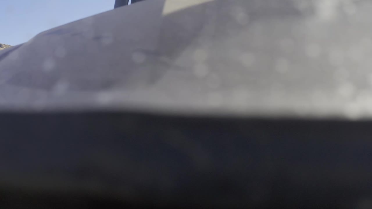 Second frame from Baja California Sur Mexico footage with the gray shape still filling most of the top half, a dark band below, a faint blue sky corner, and no visible people.