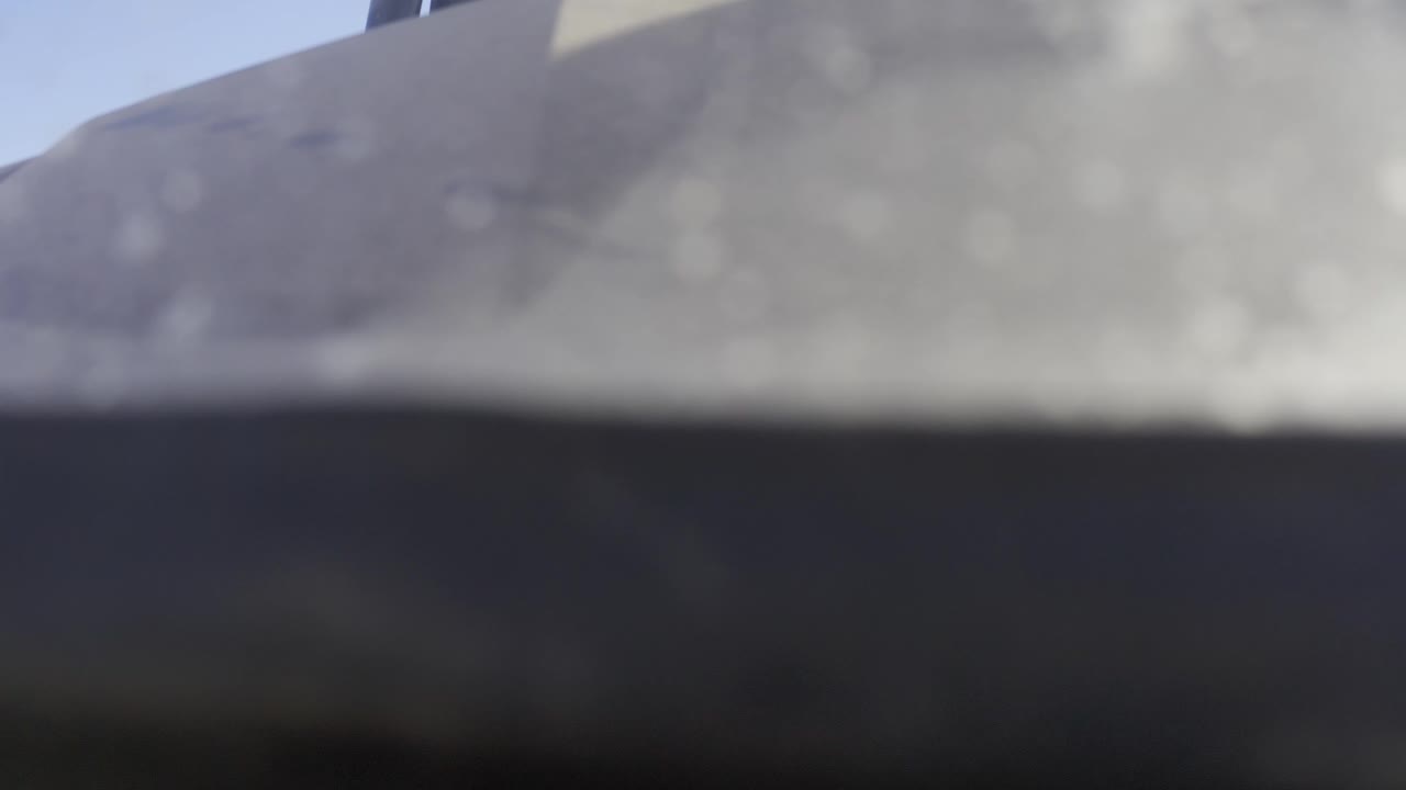 Third frame from Baja California Sur Mexico footage where the gray upper form and dark lower band remain soft, with a slightly clearer blue sky sliver at the left and no visible people.