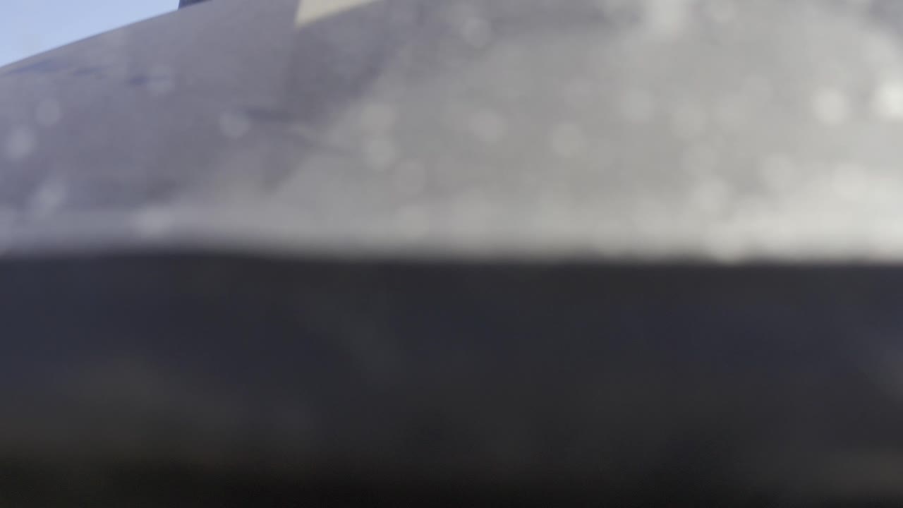 Soft, blurry close view of a pale gray rock-like surface in Baja California Sur, Mexico, with a darker band across the lower frame and no visible people.
