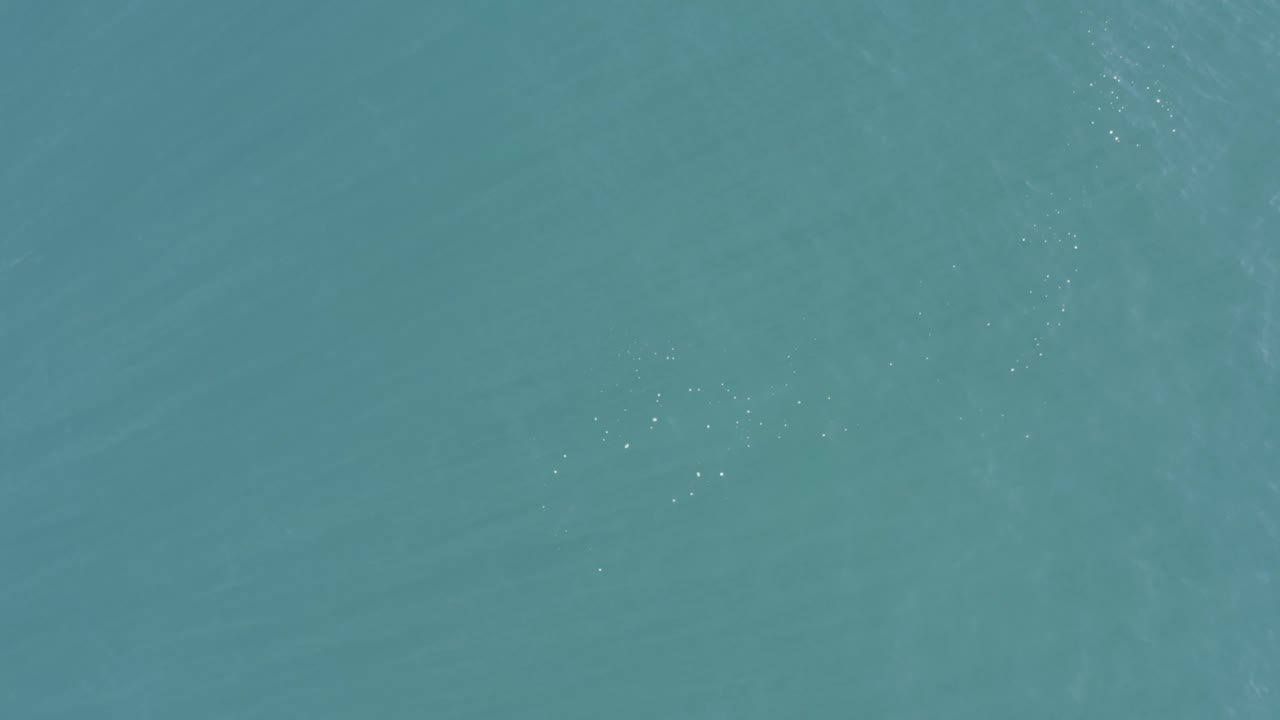 Aerial view of open Baja California Sur ocean water, with scattered white glints on the surface and no visible people.
