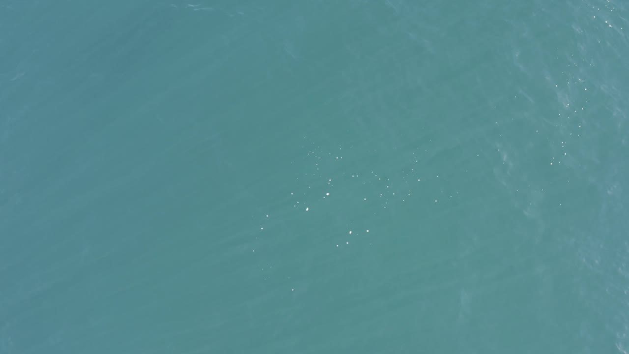 Calm teal ocean in Baja California Sur, Mexico, showing pale wave streaks, tiny light sparkles, and no visible people or objects.