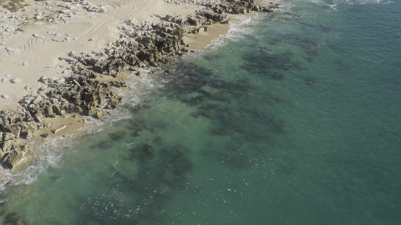 Aerial view of clear water beside sandy rocks