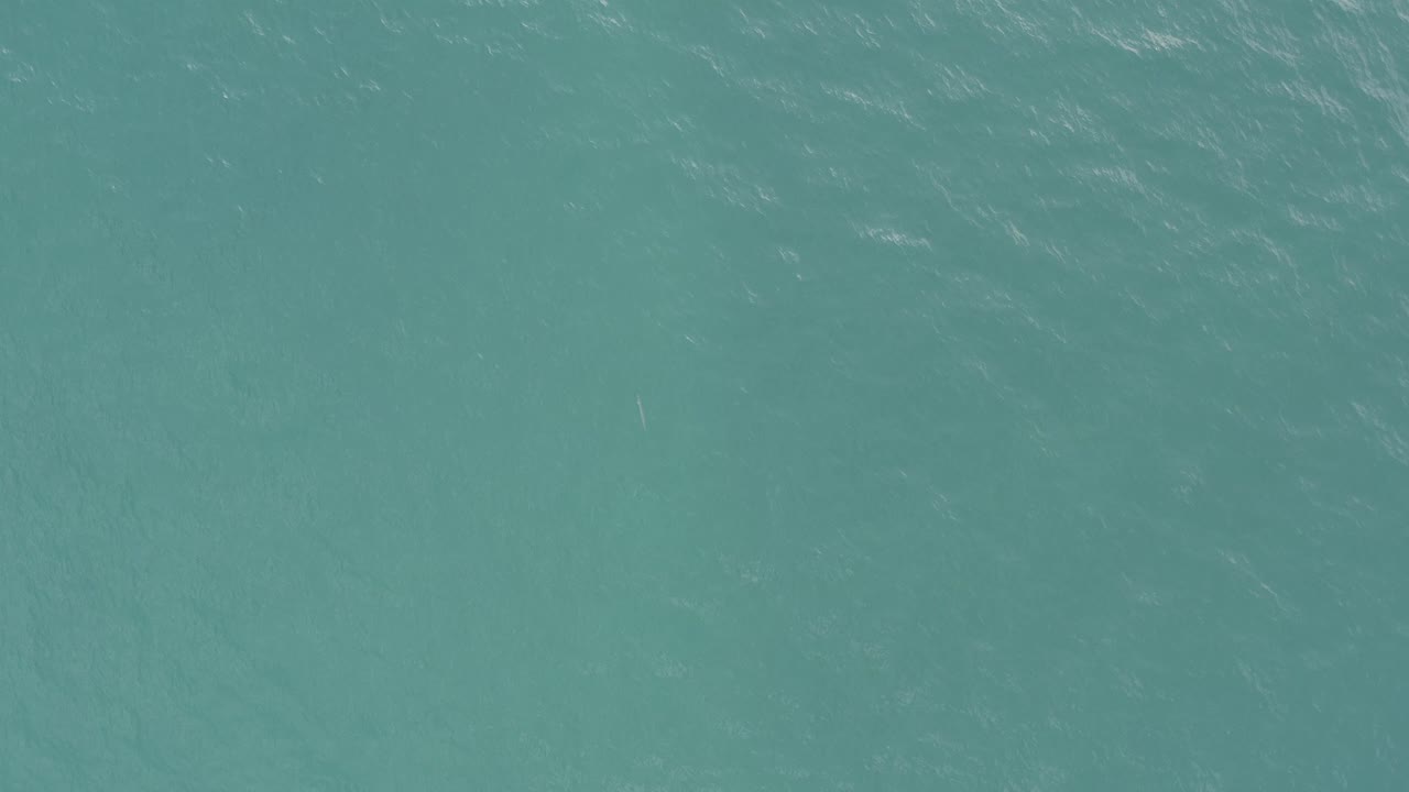 Top-down ocean view in Baja California Sur, Mexico, showing pale ripple streaks across turquoise water and no visible people.