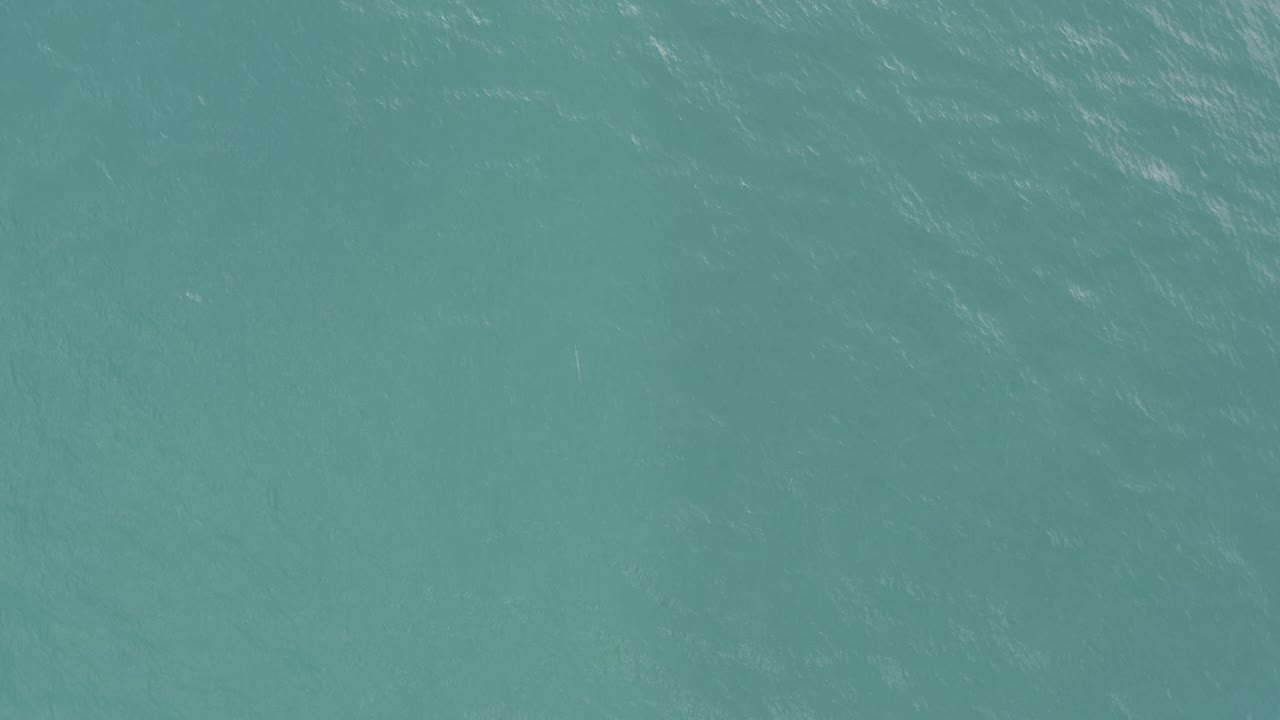 Aerial view of turquoise sea in Baja California Sur, Mexico, with diagonal light ripples crossing the water and no visible people.