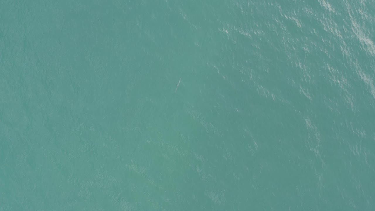 Direct overhead view of rippling turquoise water in Baja California Sur, with a muted silver sheen and no visible people.
