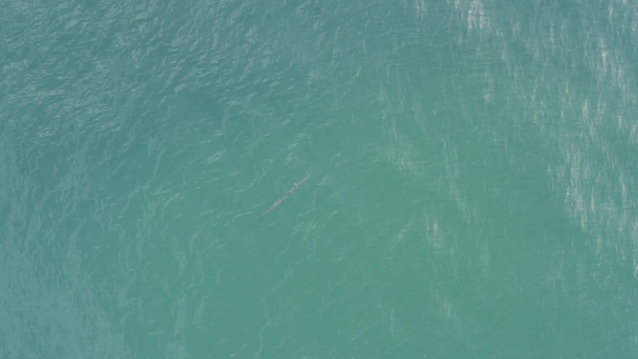 Top-down view over Baja California Sur water with teal color, fine wave texture, brighter glare bands to one side, and no visible people.