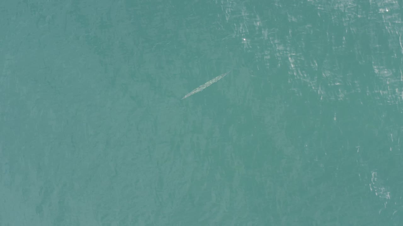 Rippling turquoise water with faint underwater texture and a gray streak.