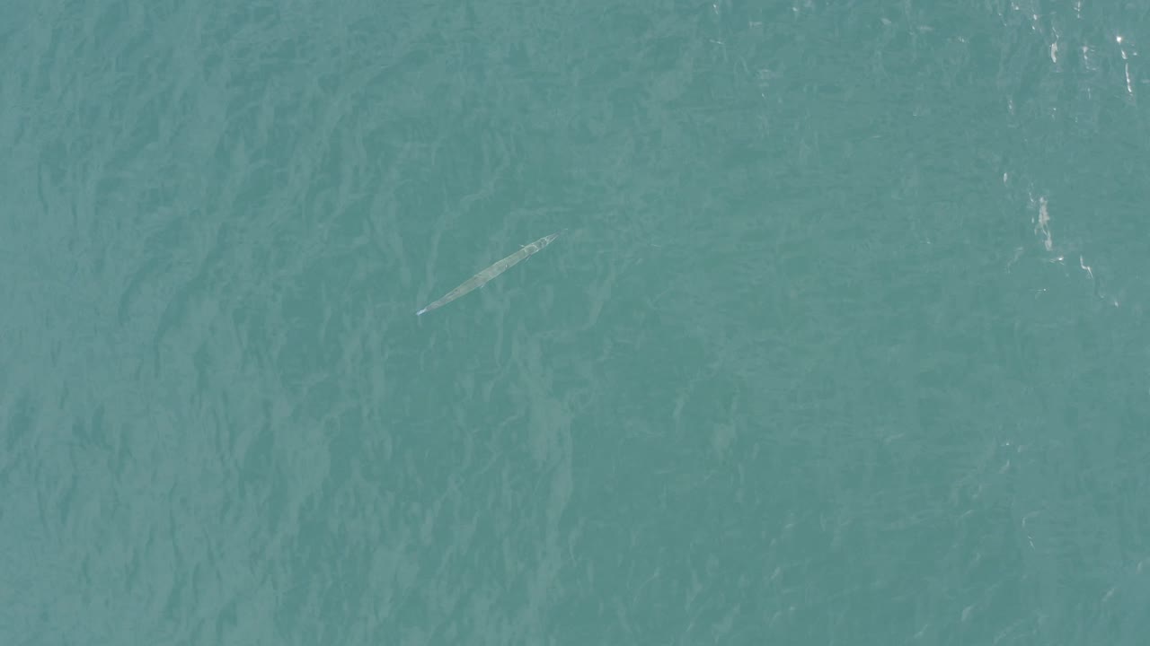 Turquoise sea in Baja California Sur, Mexico, shows a pale submerged streak near the upper portion of the frame, fine wave texture, and no visible people.