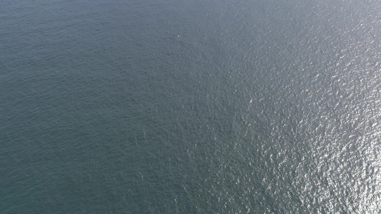 Blue-green sea surface in Baja California Sur, Mexico, fills the frame with fine ripple patterns and a pale silver highlight toward the right edge, no visible people.