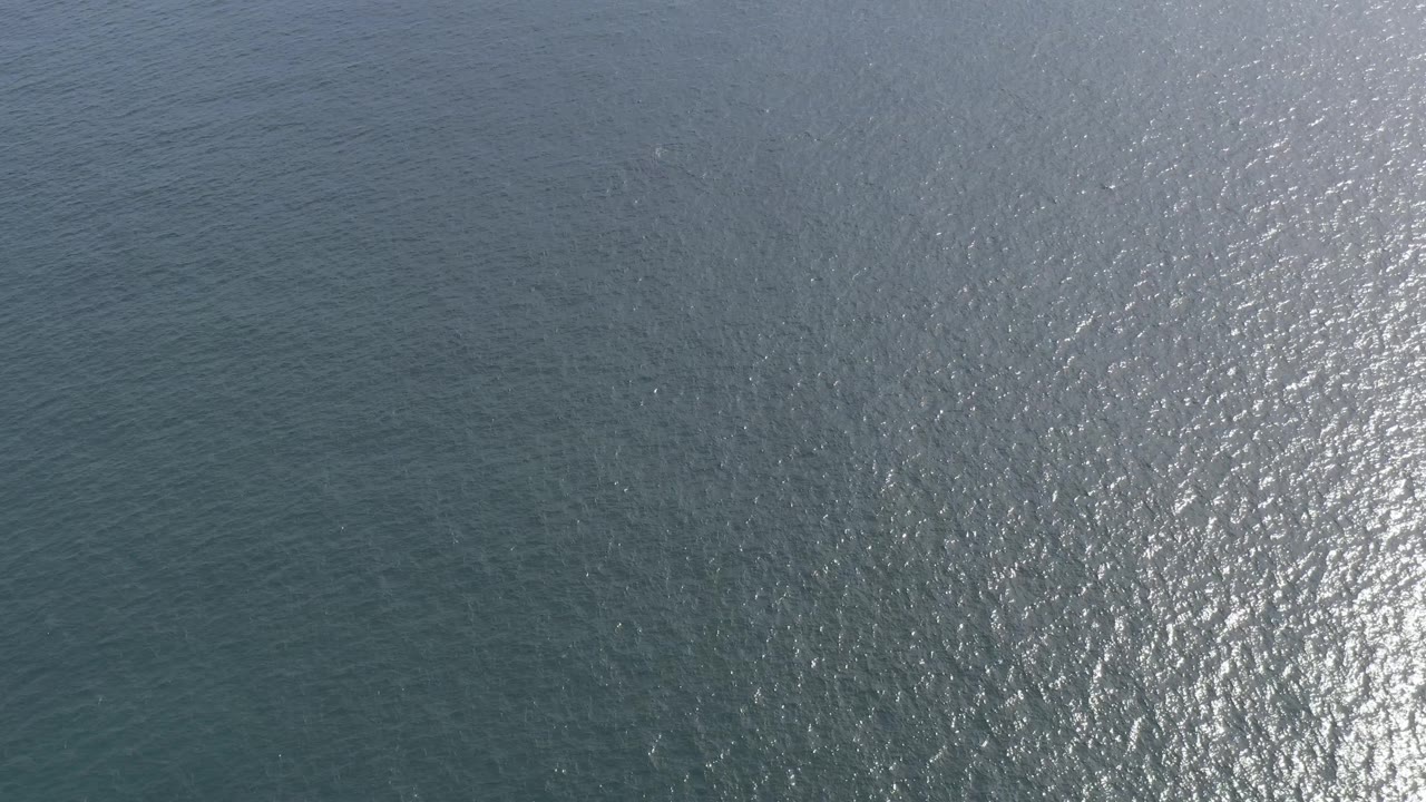 Aerial-looking view of wind-ruffled ocean in Baja California Sur, Mexico, with darker water at left and a denser patch of sun sparkle on the right, no visible people.