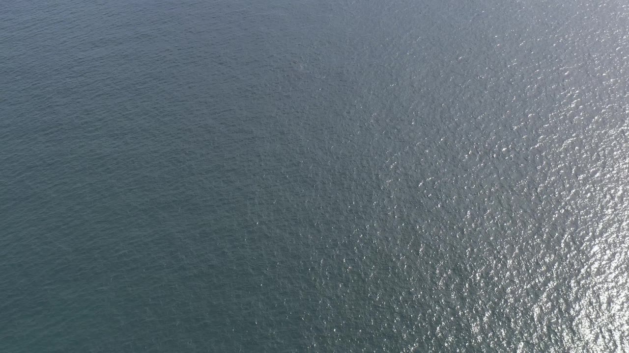 Blue ocean water in Baja California Sur, Mexico, fills the frame with low wave texture and right-side glare from the sun, no land, boats, animals, or visible people.