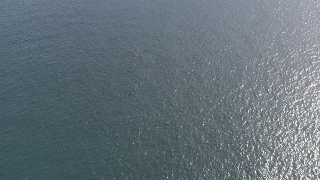 Open ocean surface with shimmering light on small waves.