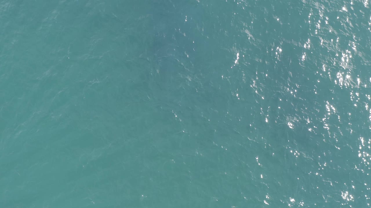 Turquoise water in Baja California Sur, Mexico, with dense sun sparkle crossing the left side of the frame and no visible people.