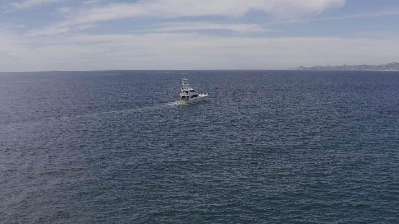 The boat appears left of center on Baja California Sur coastal water, leaving a longer pale wake across the darker rippled sea with no visible people.