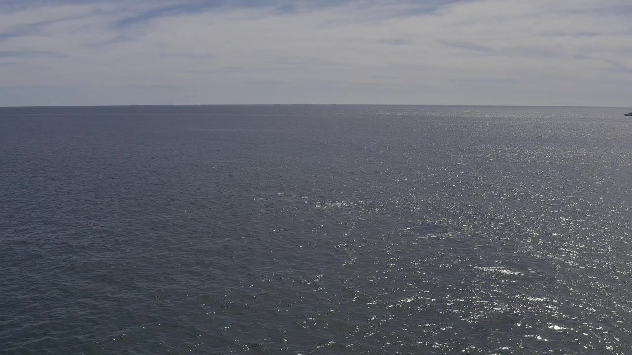 Open ocean with bright sunlight reflecting across small waves.