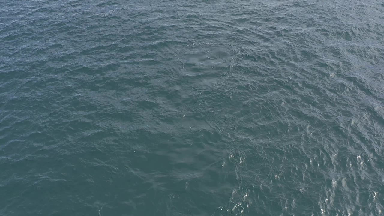Textured ocean water fills the frame in Baja California Sur, Mexico, with pale wave marks running through darker teal patches and no visible people.