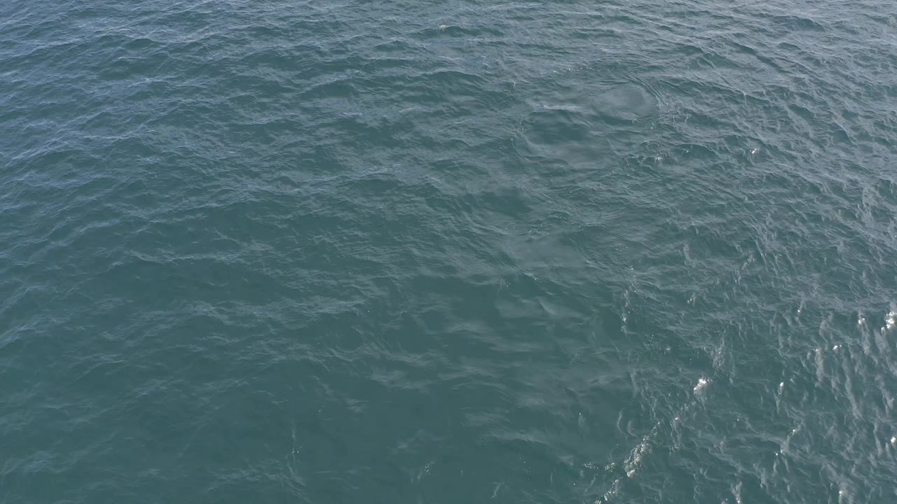 Close aerial view of rippled ocean water with scattered white highlights.