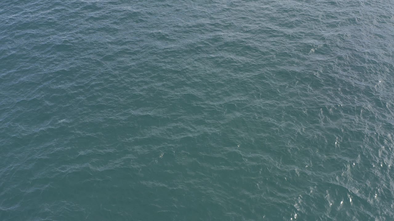 Opening frame of teal ocean water in Baja California Sur, Mexico, seen from above with fine ripples, faint foam lines, and no visible people.