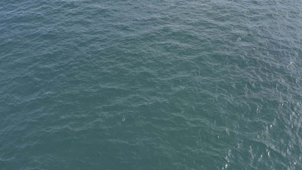 Teal water surface in Baja California Sur, Mexico, fills the frame as ripple patterns shift slightly and small sun glints appear, with no visible people.