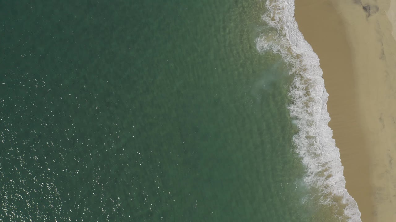 Overhead ocean waves meeting a sandy beach.