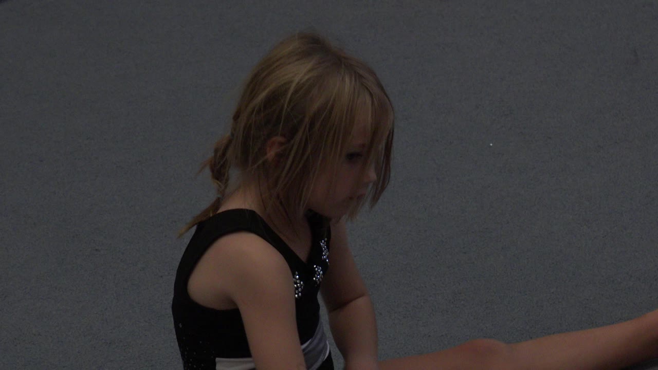 The child remains seated on the gray floor in Cabo San Lucas footage, with her blonde hair partly covering her face and one leg extended out of frame.
