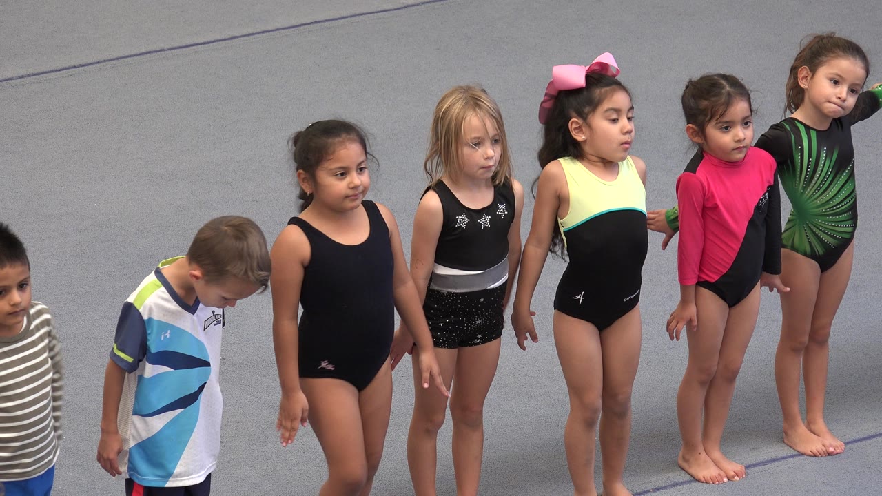 The children remain in a line in Cabo San Lucas, with a boy looking down, girls standing barefoot, and several hands linked across the group.