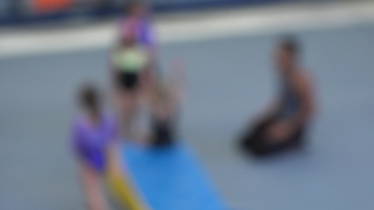Blurred gym class with children and instructor near a wedge mat.