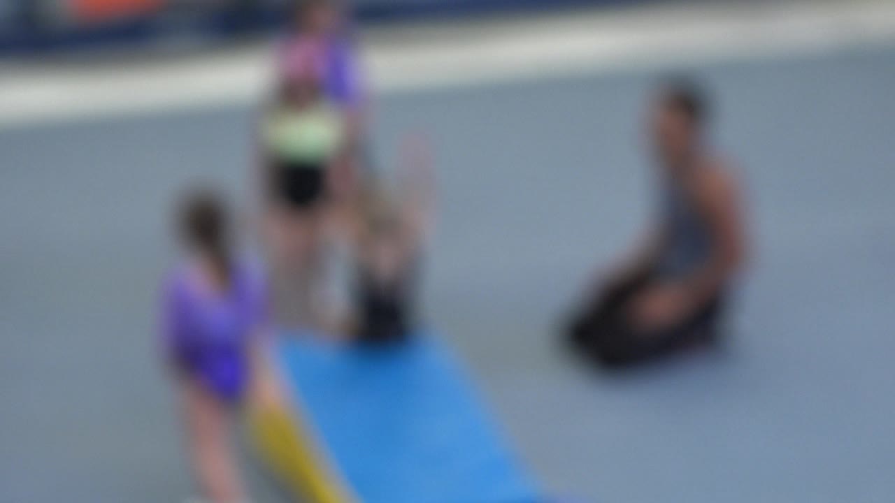 A second blurred frame in Cabo San Lucas keeps the children, kneeling teacher, and padded incline mat visible from the elevated side angle.