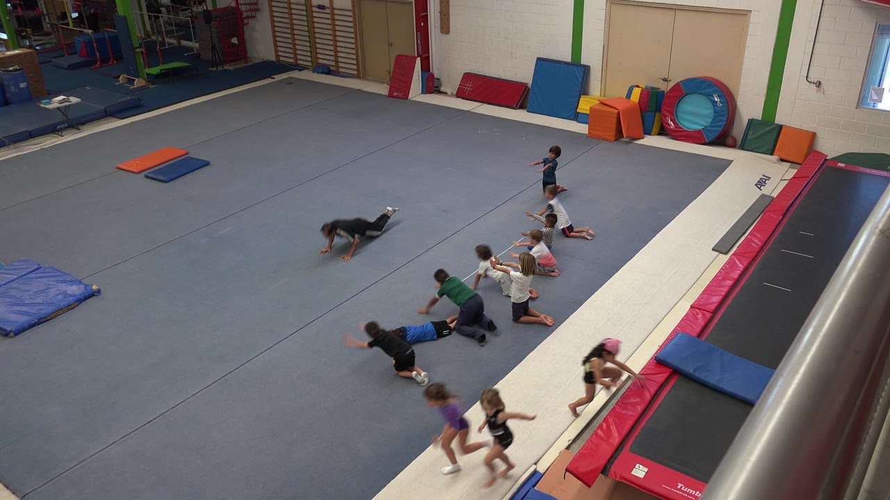 Children and an adult begin floor movement beside the trampoline.