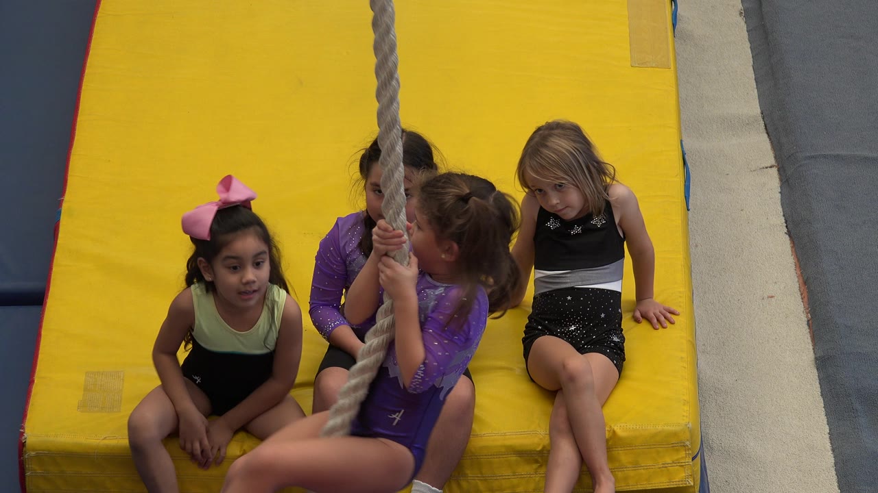A child grips the rope in front of seated friends.