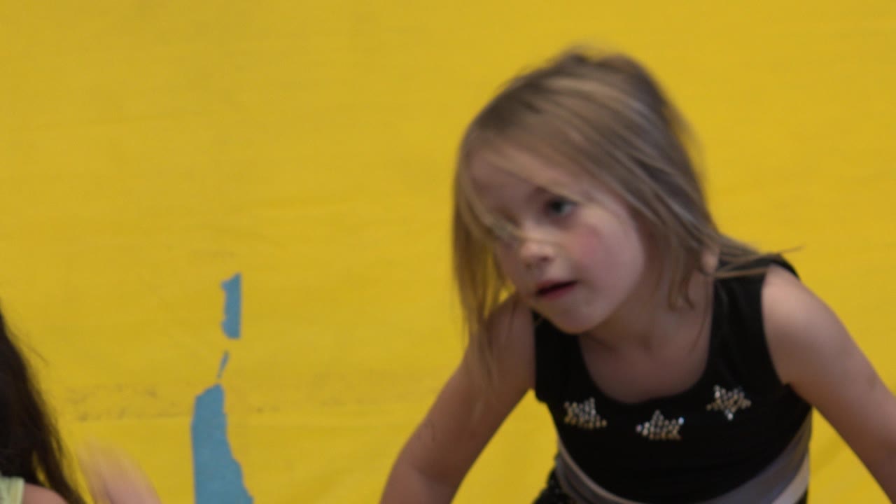 A blonde girl is framed near the yellow padded wall.
