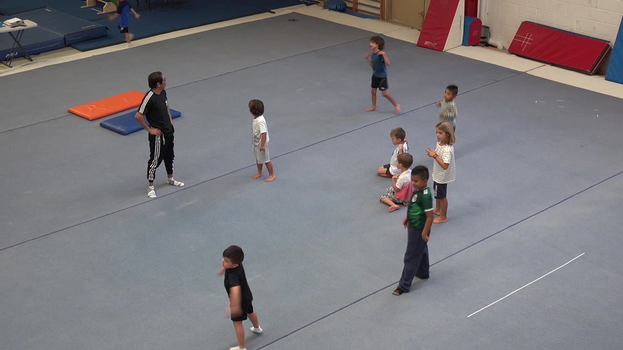 Coach and children spaced across a gray gym floor.