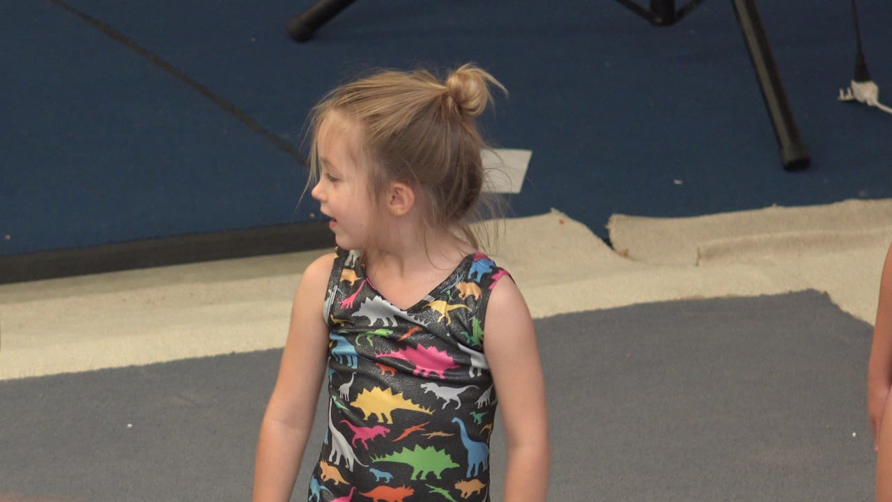The same young child remains turned to the left in Cabo San Lucas, Mexico, with the gray mat and dark wall visible behind her.
