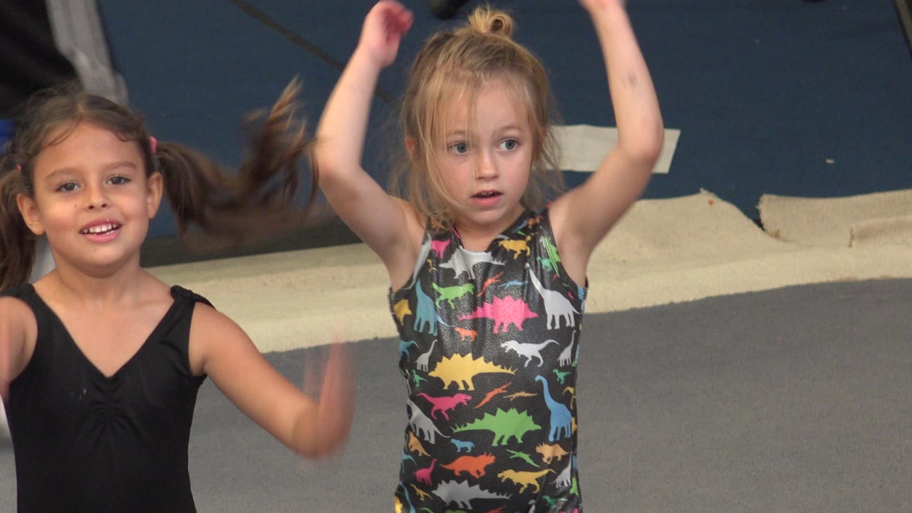 The two girls continue the warm-up in Cabo San Lucas, with the girl in black smiling toward camera and the blonde girl holding both arms high.