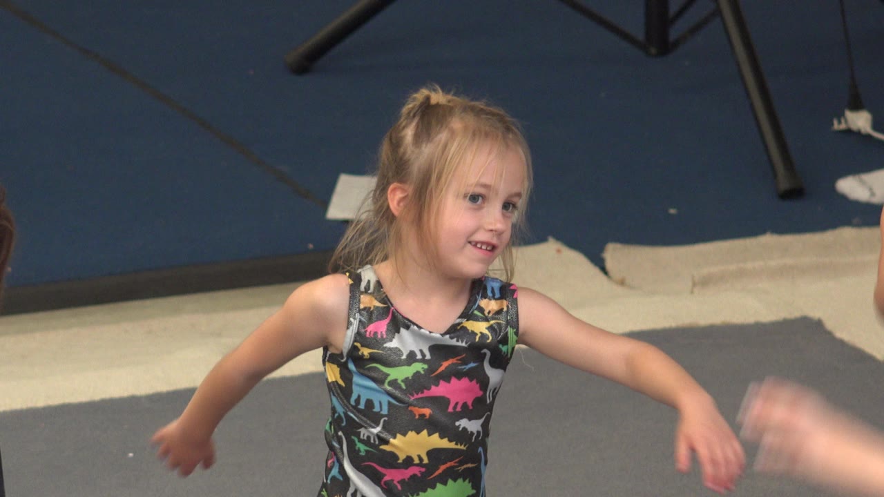 Young blonde girl dancing on a gray floor