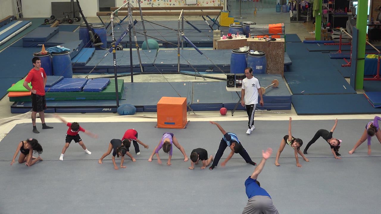 Children and instructors during a gym class warmup.