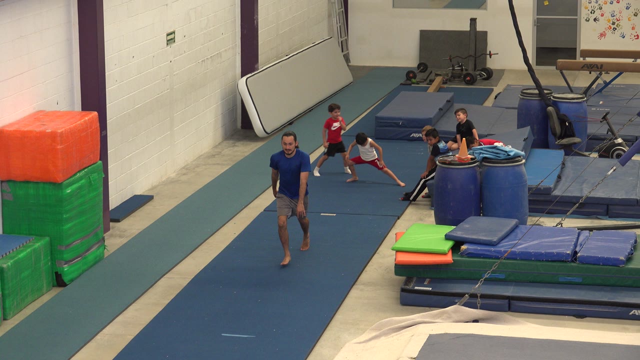 Coach and children on a gymnastics runway mat