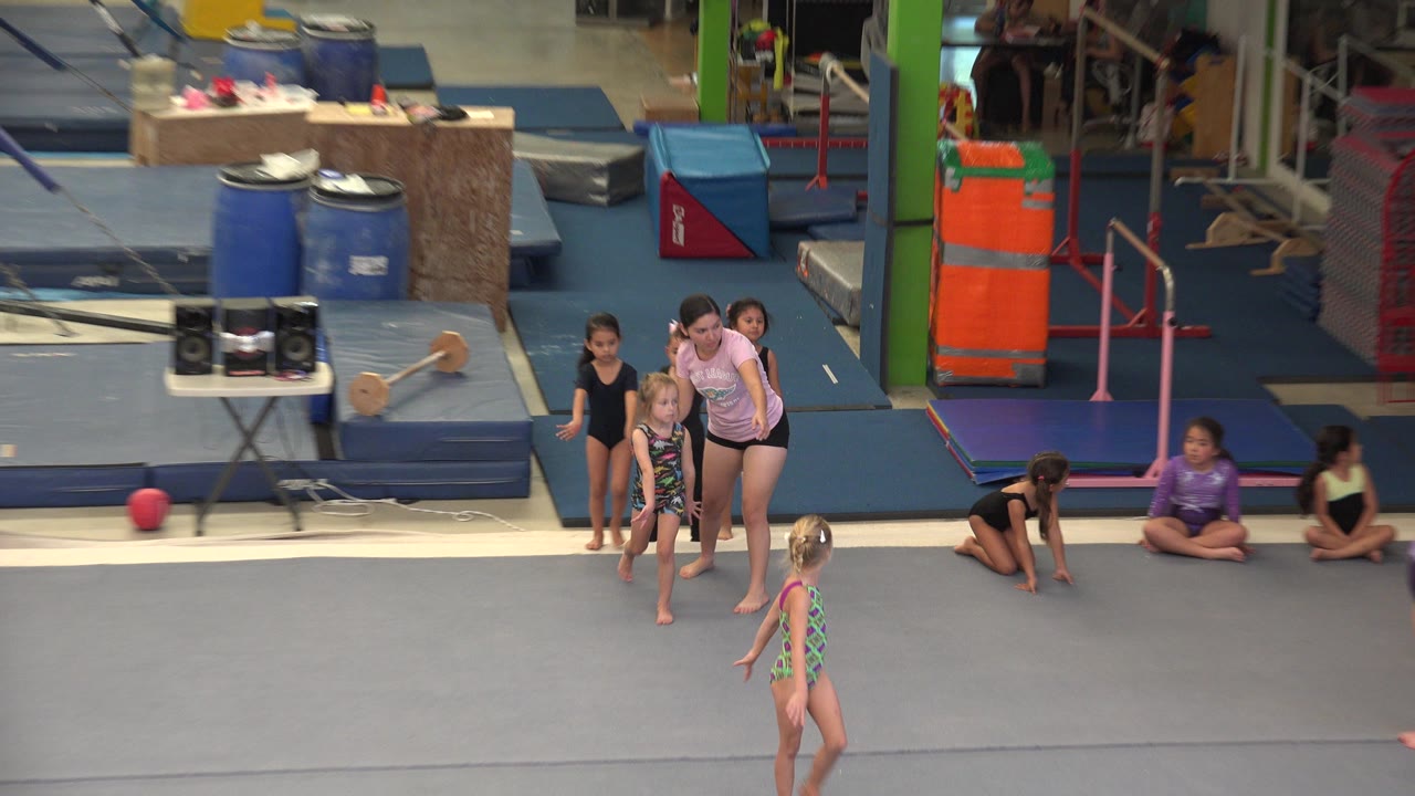 Young girls walking barefoot across a gym floor during class.