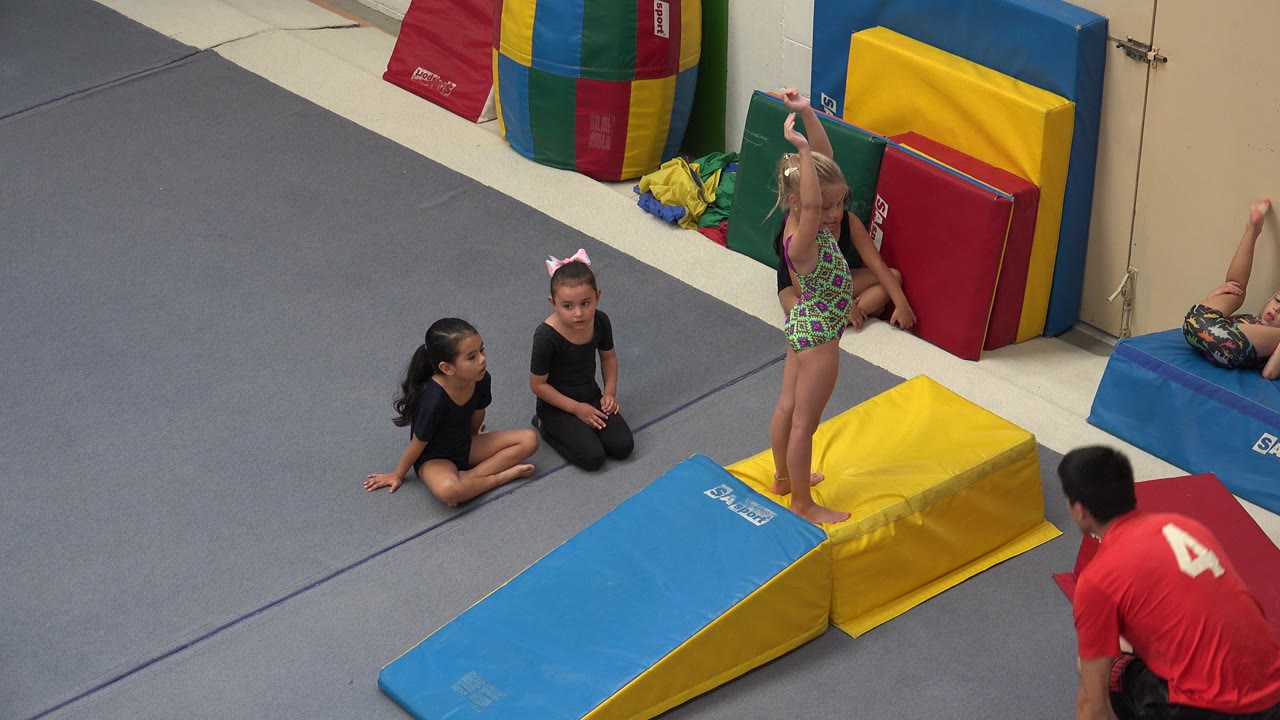 In Cabo San Lucas, Mexico, the girl remains upright on the padded wedge as two children sit to the left and the instructor stays low near the mat.
