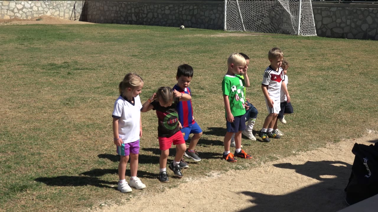Children standing and stepping on a sunny sports field.