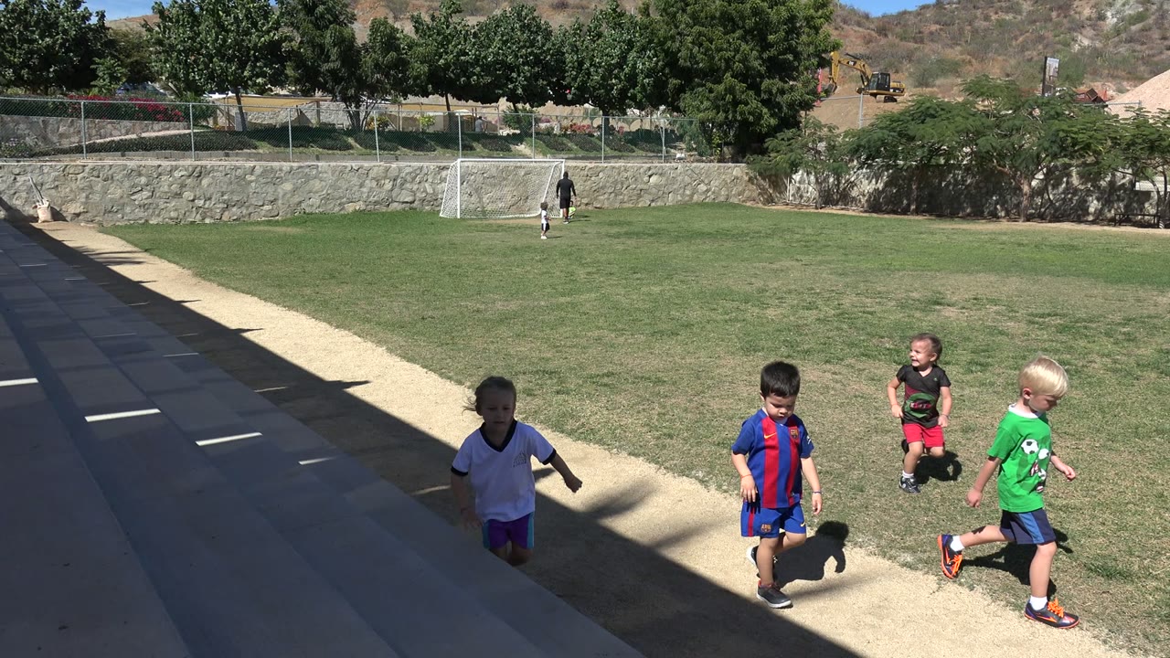 Children walking near steps beside a soccer field.