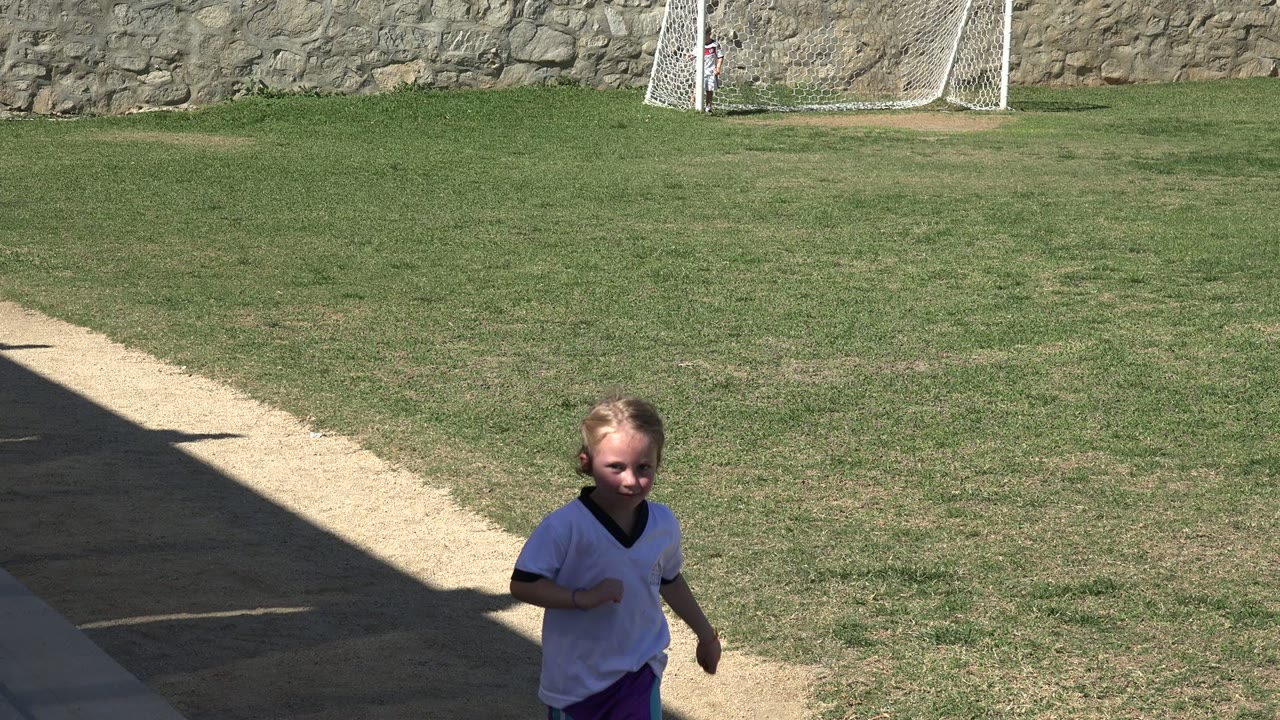 Girl passing near the right edge of a soccer field frame.