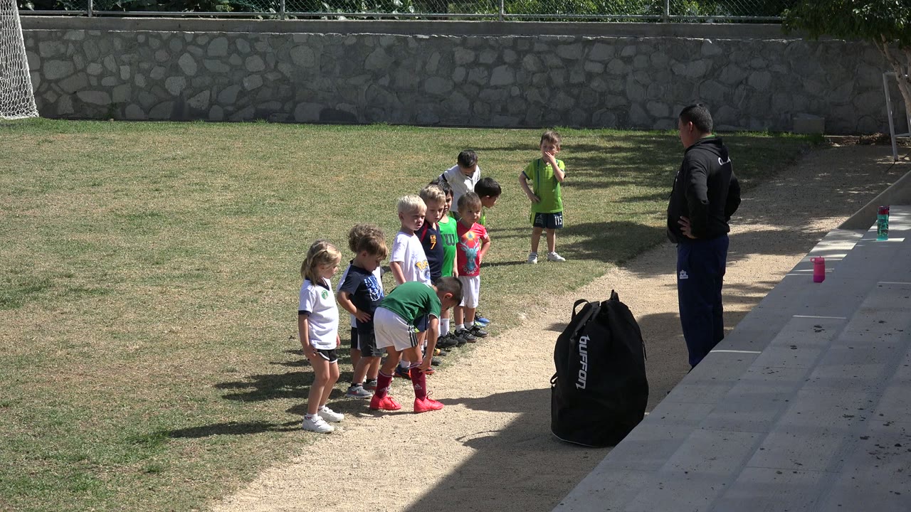 A child bends forward as teammates wait in line.