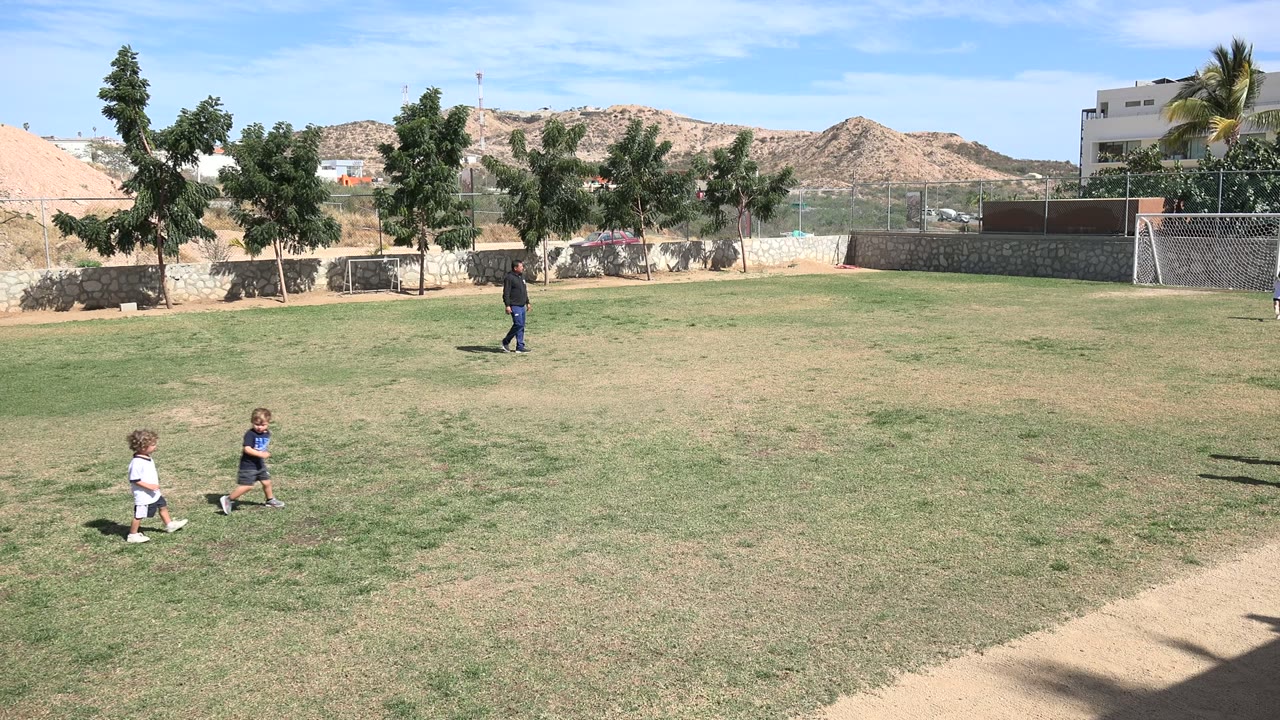 Children on a grassy field with an instructor in the distance.